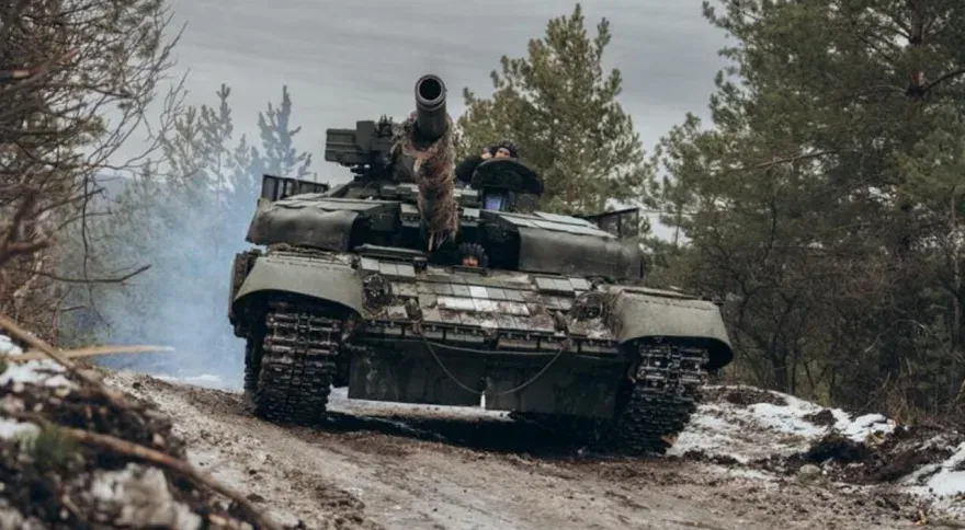 Танк із командиром у люку рухається розбитою лісовою дорогою.